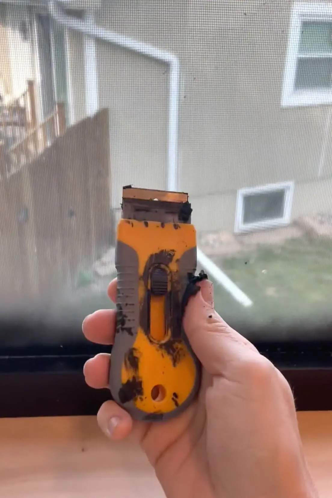 Scraping paint off of the window using a razor blade.
